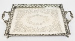 TABULEIRO EM PRATA DE LEI COM GALERIA VAZADA E PLANO COM GUILLOCHES FORMANDO LAURÉIS. ALÇAS LATERAIS. PÉS EM GARRA. MARCAS DO PRATERIO UNIÃO. BRASIL, MEADOS DO SEC. XX. 40 CM DE COMPRIMENTO