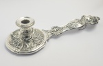 RARA PALMATÓRIA EM PRATA DE LEI COM PORTA TOALHAS. PEGA DECORADA COM CABEÇA DE QUERUBIM. BRASIL, PRINCIPIO DO SEC. XIX. 35 CM DE COMPRIMENTO NOTA: O rito do batismo envolve a entrega simbólica da chama que representa a luz de Cristo. Para tanto as palmatórias de batismo tinham emprego na cerimonia, sempre com um longo cabo para pega, apresentavam os mais diferentes e requintados feitios. No momento do batizado, a madrinha segura a criança e o padrinho fica ao seu lado.. E, após o ritual, o padrinho entrega simbolicamente uma vela acesa à criança, dizendo: Recebe a luz de Cristo. Essa vela grande é o Círio Pascal, que simboliza Cristo, a luz do mundo.