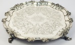 PRATA DE LEI VITORIANA - PALACIANA SALVA EM PRATA DE LEI DE GRANDE DIMENSÃO COM MARCAS PARA CIDADE DE LONDRES, LETRA DATA 1848, PRATEIROS CHARLES REILY E GEORGE STORER. UMA DAS MAIS BELAS SALVAS DESSE LEILÃO. BORDA MOVIMENTADA. PLANO COM GUILLOCHES E EM RESERVA ELABORADO BRASAO DE CAVALEIRO COM TIMBRE ARMORIAL DE FALCÃO SOBRE CHAPÉU E MOTO ECCE QUAM VIDERE. OS PÉS SÃO MARAVILHOSOS. 35 CM DE DIAMETRO. 1395 GNOTA: Charles & George Reily & Storer  eram ourives que operavam em Londres durante a primeira metade do século XIX durante os reinados de William IV e Victoria.Charles Reily tornou-se sócio de sua mãe Mary Reily e inscreveu sua primeira marca em 31 de maio de 1826 em seu endereço de oficina em Carey Lane, Londres. fizeram parceria com George Storer em 1829 quando registraram outra marca como trabalhadores de prata em 1º de janeiro daquele ano. Eles registraram sua terceira marca em dois tamanhos em 1840.   e começaram a se especializar em peças menores, pois suas marcas posteriores são encontradas principalmente em caixas de rapé de alta qualidade e outros itens menores.