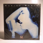 Vinil Marisa Monte MM. Produto Original. Gravadora Emi. Fabricado e distribuído por Fonobrás distribuidora fonográfica brasileira Ltda. 1989. Capa (escurecida, com pontos de oxidação e desgastes do material)/contracapa (com pontos de oxidação, escurecida e com desgastes do material) em regular estado de conservação, manchas/pontos de oxidação, marcação do disco, com sinais de uso, manuseio e desgastes. Contém plástico de proteção do disco, com rasgos. Disco com riscos, mesmo que superficiais, podem ocasionar algum nível de ruído na audição. Contém encarte. Lado A 6 faixas. Lado B 5 faixas.