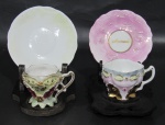 PORCELANA, Duas xícaras de coleção com seus respectivos pires em porcelana esmaltada, sendo: A) 1 na tonalidade branca, com pintura de flores em douração, realces em relevo com douração (4,5x7x5cm) e B) 1 com pintura furtacor em policromia, decorada com flor em relevo com vasta douração, pires adaptado na tonalidade rosa (4,5x7x5cm).