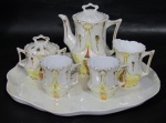 PORCELANA, Conjunto de tête-à-tête em porcelana esmaltada furtacor, decoração em relevo com pintura amarela com vasta douração, sendo: A) 1 bandeja com inscrições em dourado com falhas (24,5cm), B) 1 bule (11x11x6cm), C) 1 açucareiro, tampa quebrada e colada (6,5x8x5,5cm), D) 1 leiteira, apresenta 1 bicado (7x7x5cm) e E) 2 xícaras (5,5x6cm)