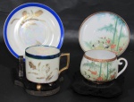 PORCELANA, Duas xícaras de coleção com seus respectivos pires em porcelana esmaltada, sendo: A) 1 com pintura dita furtacor com espessa faixa na tonalidade azul, flores e folhagens em ouro, apoiado sobre 3 pés (6x7x5,5cm) e B) 1 com pintura de bambuzais, flores, folhagens e animais em policromia pintado a mão (5x7,5x6cm).