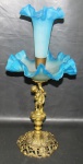BRONZE, Fruteira com floreira em vidro moldado na cor azul degradê. Corpo em bronze, sustentado por figura representando Puttino, base ricamente cinzelada por elementos vegetalistas e vazados. Med.: 51x25cm.