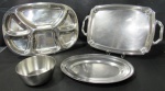 METAL INOX, Quatro peças em aço inox, sendo: A) 1 petisqueira com 6 divisórias da manufatura MERIDIONAL (44,5x32,5cm), B) 1 bandeja decorada com volutas, alça lateral possui mossa (48x31cm), C) 1 travessa oval (36,5x25,5cm) e D) 1 tigela da manufatura TRAMONTINA (7,5x17cm).