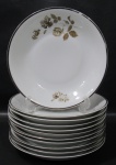 RENNER, Medaillon, Onze pratos fundos em porcelana esmaltada na tonalidade branca com pintura de flores e folhagens em policromia, borda filetada a prata. 2 com falhas na prateação Med.: 22,5cm.