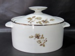RENNER, Medaillon, Sopeira em porcelana esmaltada na tonalidade branca com pintura de flores e folhagens em policromia, borda filetada a prata, alças laterais e pega da tampa no formato de disco. Med.: 15x26x21cm.