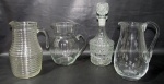 CRISTAIS/VIDROS, Lote com 4 peças, sendo: A) 1 refresqueira em vidro translucido com corpo em gomos (22x15,5x9,5cm), B) 1 garrafa para whisky em vidro translucido ricamente lapidado (29cm), C) 1 jarra em vidro translucido com corpo liso (19,5x17x11cm) e D) 1 jarra em cristal translucido lapidado em baixo relevo (21,5x16x9cm).