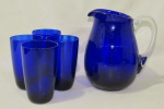CRISTAIS, Refresqueira e 4 copos em cristal na tonalidade azul, corpo com decoração canelada e pega da refresqueira translucida. Med.: Refresqueira (18x16x9,5cm) e copos: (12x7,5cm).