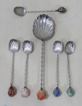 METAL PRATEADO, Seis colheres em metal espessurado a prata no feitio de concha, cabo torcido terminado em pedras brasileiras distintas, sendo: 1 para arroz e 5 para sobremesa.