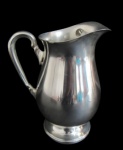 METAL PRATEADO, Refresqueira em metal espessurado a prata, corpo bojudo, base circular escalonada, aparador de gelo. Med.: 21x11x17,5cm. Duas pequenas mossas.