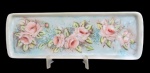 PORCELANA, Travessa para rocambole em porcelana esmaltada na tonalidade branca, com pintura de flores e folhagens em rica policromia, assinado Lourdes Valente, Rio 24/10/86. Med.: 39x13,5cm.