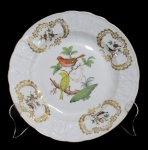 HEREND, Hungria, Prato decorativo em porcelana esmaltada na tonalidade branco, decorado com pássaros e folhagens em policromia, elementos vegetalistas em ouro e relevo. Marcado no fundo. Med.: 25cm.