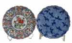 IMARI, Japão, Dois pratos decorativos em porcelana japonesa esmaltada, sendo; A) 1 com pintura de flores, folhagens e elementos vegetalistas e geométricos em rica policromia, marcado no fundo (19cm) e B) 1 com pintura de garças na tonalidade azul (19cm), ambos marcados no fundo.