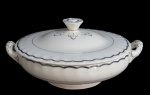 GRINDLEY, Inglaterra, Terrina em faiança vitrificada, borda ondulada, espessa faixa em prata, apresenta craquele. Med.: 12x26x22cm.