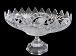 CRISTAIS, Grande fruteira em cristal europeu translucido, ricamente lapidada por sulcos, estrelas, esferas, e folhagens, flores em satine, borda dentada, haste facetada oitavada. Med.: 20,5x33x19cm.