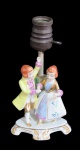 ABAJUR, Abajur para 1 lâmpada em porcelana esmaltada na tonalidade branca representando casal, com pintura policromada e adornos em ouro. Med.: 19x11x9cm.