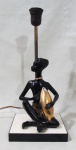 LUMINÁRIAS, Luminária para 1 lâmpada, estrutura em metal dourado, representando figura feminina africana em porcelana esmaltada sobre base de madeira. Apresentam falhas na esmaltagem. Med.: 35cm.