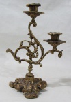 ARTE SACRA, Candelabro para 2 velas, confeccionado em bronze, decorado por motivos vegetalistas e vazados, pés tripoides ricamente cinzelado. Med.: 25x16,5cm.