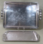METAL PRATEADO, Duas bandejas, sendo: A) 1 em metal espessurado a prata. borda cinzelada por caneluras e fitas cruzadas (45x32cm) e B) 1 em aço inox ricamente cinzelada por motivos florais (36x20cm).