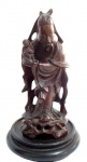 ESCULTURAS, Escultura oriental confeccionada em madeira entalhada, representando figura oriental segurando criança, apoiada sobre peanha em madeira com base escalonada. Possui 1 bicado. Med.: 18cm / Peanha: 11,5cm.