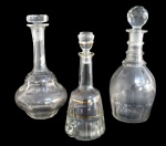CRISTAIS/VIDROS, Lote com 3 garrafas, sendo: A) 2 licoreiras em cristal translucido com lapidação dita: Dedão (28cm trincada, 25,5cm tampa adptada) e B) 1 licoreira em vidro translucido, decorado em gomos e filetes em ouro, falhas na douração (22,5cm)