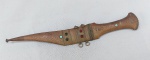 CUTELARIA, uma (1) adaga árabe, dita Jambiya, cabo em madeira com acabamento em metal com aplique de cabochões em vidros coloridos, bainha soldada no cabo, não dá para ver a lâmina, medindo 27,5 cm comprimento.