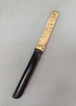 CUTELARIA, um (1) TANTO, com lâmina em aço (sinais de oxidação), empunhadura confeccionada em marfim e/ou osso, entalhes figurativos representando cotidiano oriental, possui defeitos e pequenas perdas, bainha em madeira laqueada com acabamento em latão, vide foto, medindo 31,5 cm comprimento.