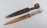 CUTELARIA, um (1) antigo punhal com lâmina em aço (bastante sinais de oxidação) da marca KORIUM, origem alemã da região de Solingen, marcados na lâmina e na bainha em couro com ponteira em metal, cabo fundido em alumínio ou antimônio com terminação em garra segurando uma esfera, medindo 26 cm comprimento, vide foto.