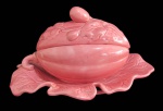 FAIANÇA, Molheira acondicionada a presentoir, confeccionada em faiança vitrificada, representando fruto, esmaltado na tonalidade rosa. Possui colados e bicados. Med.: 17x31x22cm.