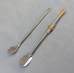 DIVERSOS, duas (2) bombas distintas para chimarrão, confeccionadas em metal prateado, ambas com patilha fixa, haste cilíndrica e boquilha continuação da haste, uma delas sem botão de rosa, outra com botão de rosa relevado em elementos vegetalistas e detalhes em dourado, não aparentam terem sido usadas, ambas sem marca de manufatura aparente e medindo 20,5 cm comprimento.