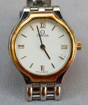 RELÓGIO, um (1) de pulso da marca OMEGA WATCH (em 1848 começou em uma pequena oficina em La Chaux de Fonds na Suíça, fundada por Louis Brandt; em 1879 Louis faleceu e seus filhos assumiram o negócio; em 1885 lançaram seu primeiro relógio produzido em massa; em 1892 lançaram seu primeiro relógio de repetição; em 1905 passou a ser o cronometrista oficial dos eventos esportivos na suíça; em 1932 foi o cronometrista dos jogos Olímpicos de Los Angeles, parceria que continua até a atualidade, atuando em mais de vinte Jogos Olímpicos; em 1962 seu modelo Speedmaster foi usado por um astronauta na missão Mercury Sigma 7; em 1965 a NASA tornou o modelo oficial para as Missões Espaciais; em 1969 fez a primeira viagem a lua; em 1990 ganhou popularidade como relógio oficial de James Bond), movimento quartz, mostrador com algarismos romanos, caixa e pulseira em metal prateado com detalhes em dourado, medindo 23 mm diâmetro, aparentemente em bom estado, usado, não testado e sem garantia, possivelmente demanda bateria.