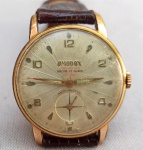 RELÓGIO, um (1) antigo de pulso da marca OMODOX, Suíço, modelo DE LUXE mecânico, funcionando, a corda, mecanismo com 17 rubis ou safiras, mostrador com algarismos arábicos, caixa em metal dourado, medindo 31 mm diâmetro, tampa em aço inox, pulseira em couro, usado, funcionando e sem garantia.