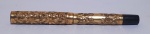 CANETAS - Uma caneta tinteiro em metal dourado e baquelite, ricamente cinzelado por flores, possui pequeno bicado na parte inferior. Med.: 13cm.