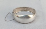 JOIA, um (1) bracelete rígido, confeccionado em PRATA, liso, possui pega ladrão, medindo 6,5 x 5,5 cm, largura maior 2,8 cm, peso aproximado 40 gr.