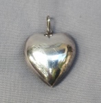 JOIA, um (1) pingente na forma de coração, confeccionado em PRATA, oco e liso, medindo 3,2 x 3,2 cm mais olhal e argola, peso aproximado 9,5 gr.