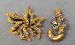BIJUTERIAS, dois (02) broches confeccionados em metal dourado e prateado, tendo num deles aplicação de esmalte preto; medindo aproximadamente 5cm.