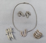 BIJUTERIAS, lote com quatro (04) itens em metal dourado e prateado com pedraria: conjunto de 1 colar shoker com pingente central fixo e 1 par de brincos de pressão; 1 broche representando pássaros; 1 anel aro 18; medida do shoker 40cm aproximadamente.