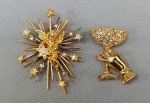 BIJUTERIAS, dois (02) broches confeccionados em metal dourado e pedrarias: 1 representando mão segurando taça e 1 com anjo tendo atrás os 7 desejos; medindo o maior 7,5 x 6cm.