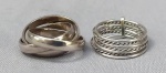 JOIAS, duas (2) alianças distintas, confeccionadas em PRATA: 1 modelo dito Cartier, com três aros entrelaçados, tamanho 18, 1 com sete aros paralelos intercalados entre liso e torçaide, unidos por haste, tamanho 16, peso total aproximado 11 gr.