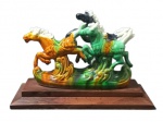 PORCELANA, Grupo escultórico em porcelana esmaltada em rica policromia representando cavalos, apoiado escalonada em jacarandá. Med.: 17x25x10cm.
