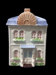 AVON, Biscoiteira confeccionada em faiança vitrificada na cor creme, representando uma casa, delicadamente pintada à mão em rica policromia, sendo a tampa em feitio de telhado esmaltado na cor rosa, marca da manufatura no fundo. Medidas 21x14x11cm. Biscoiteira possui ínfimos bicados.