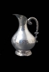 PRATARIA STERLING, Jarra d'agua/refresqueira em metal espessurada a prata, corpo bojudo, alça e base cinzelada com elementos vegetalistas. Med.: 20,5x14cm.