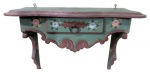 MOBILIARIO, Console de parede em madeira patinada na cor verde, tampo e saia recortados, entalhes de elementos vegetalistas, pintura de flores e folhagens em policromia, 1 gaveta central com puxador em ferro, possui rachadura e falhas na patina. Med.: 40x59x24cm.