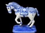DELFT, Escultura em porcelana esmaltada na tonalidade branca, representando cavalo, com pintura de elementos geométricos na tonalidade azul, sobre base retangular oitavada. Med.: 13x13x7cm.