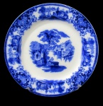 WH GRINDLEY, Inglaterra, Prato decorativo em porcelana esmaltada na tonalidade branca, com pintura de arabescos, flores, folhagens e paisagens na tonalidade dita: Azul borrão. Med.: 23cm.