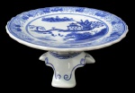 PORCELANA ORIENTAL, Fruteira de pé em porcelana esmaltada, com pintura de paisagens, elementos geométricos e folhagens na tonalidade azul, apoiado sobre 3 pés com decoração de arabescos. Med.: 10x20CM.
