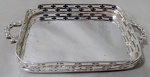 METAL PRATEADO, Pequena bandeja em metal espessurado a prata, fundo liso, galeria vazada e alças cinzeladas por arabescos. Med.: 14x8cm.
