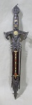 COLECIONISMO, Réplica de espada templaria de coleção com punho em metal prateado ricamente cinzelado, lâmina em aço inox, acompanha bainha em resina com aplicações em metal prateado ricamente cinzelado. Med.: 43cm.
