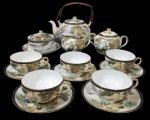 PORCELANA ORIENTAL, Parte de serviço para chá em porcelana japonesa esmaltada na tonalidade branca, dita: Casca de ovo, com pintura de paisagem com pássaros em policromia e realçados em ouro, sendo: A) 1 chaleira (18x18x8cm), B) 1 manteigueira (8x9,5x14cm), C) 1 açucareiro (8x14x6cm), D) 1 leiteira (7x10x5cm) e E) 5 xícaras para chá com seus respectivos pires, fundo de cada xícara impressos e visíveis contra luz imagem de gueixa (5x10x8,5cm).